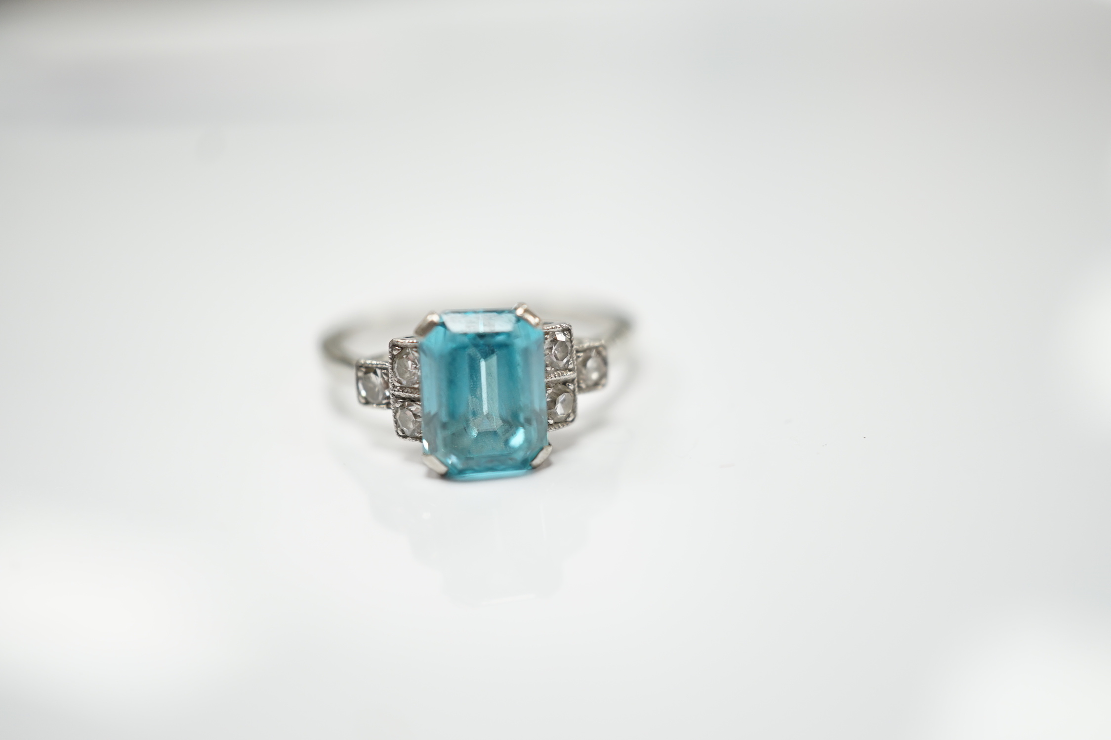 An 18ct, plat and single stone emerald cut blue zircon set ring, with six stone diamond set shoulders, size L, gross weight 2.9 grams.
